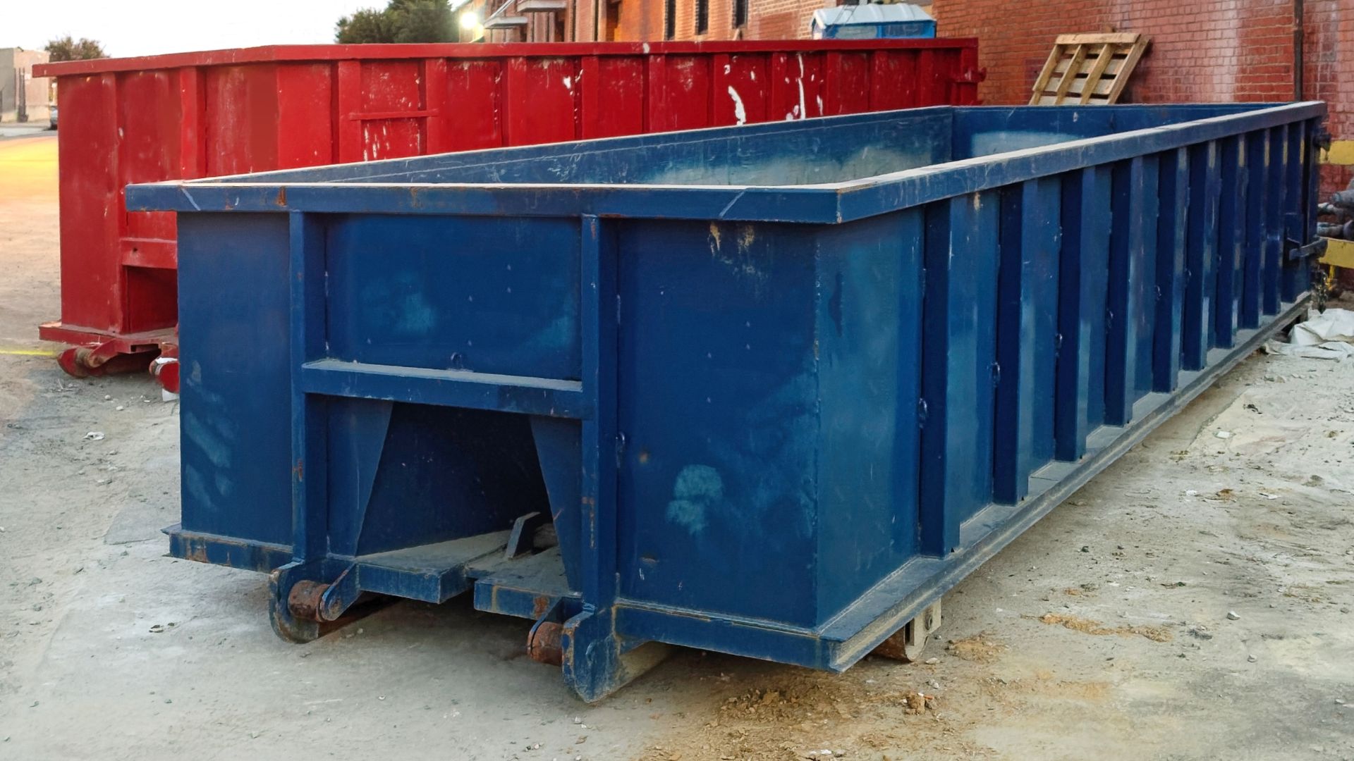 Large blue and red industrial dumpsters on construction site